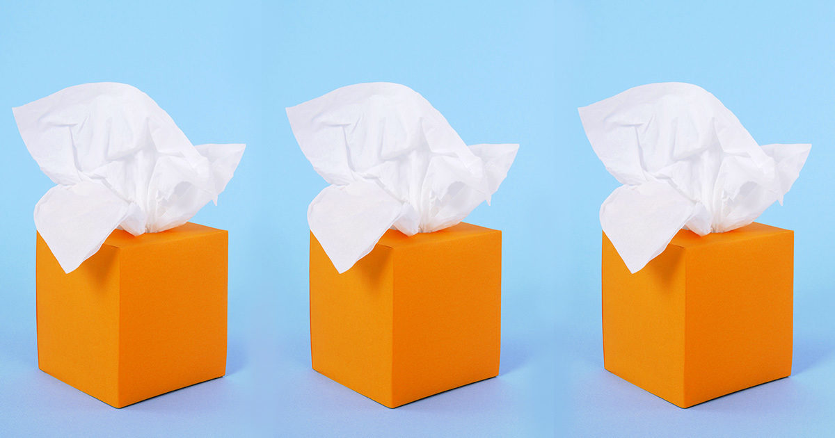 A row of three orange boxes of tissue sit in front of a bright blue background.