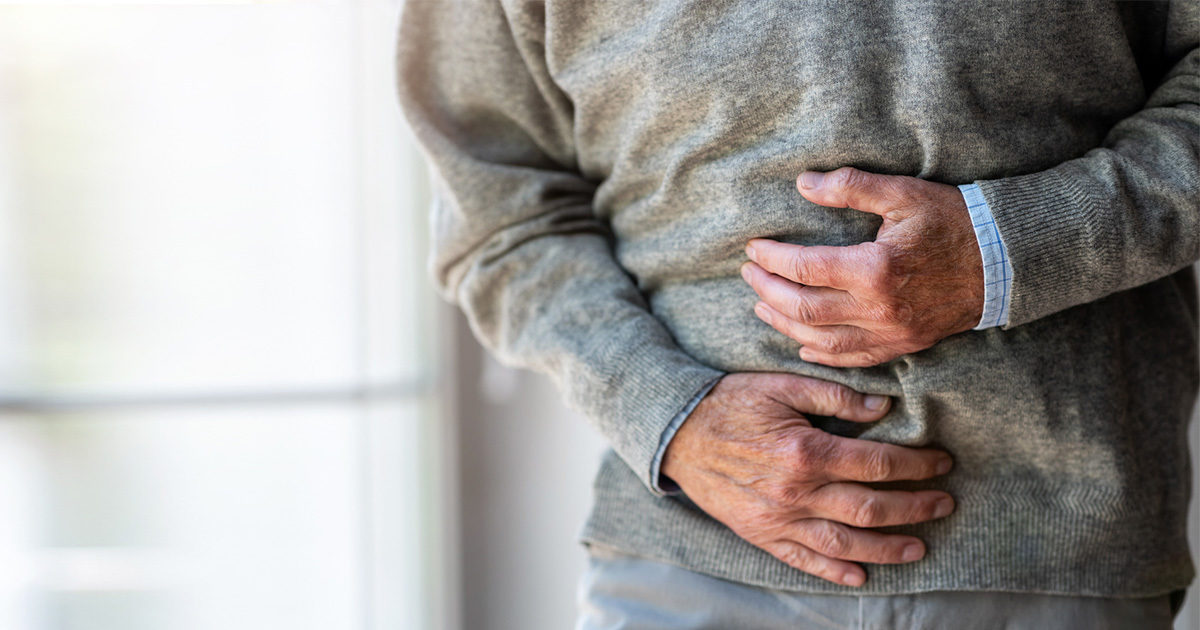 Elderly man holding stomach with both hands