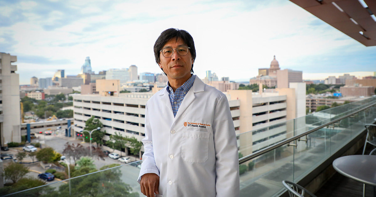 Bill Matsui, MD, Director of the Hematological Malignancies Program at the UT Health Austin LIVESTRONG Cancer Institutes, stands on a balcony overlooking Austin's downtown area.