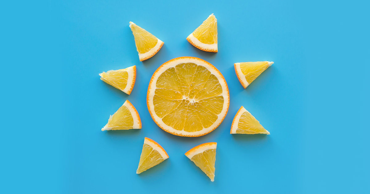 Orange slices are arranged in the shape of a sun, resting on a blue background.