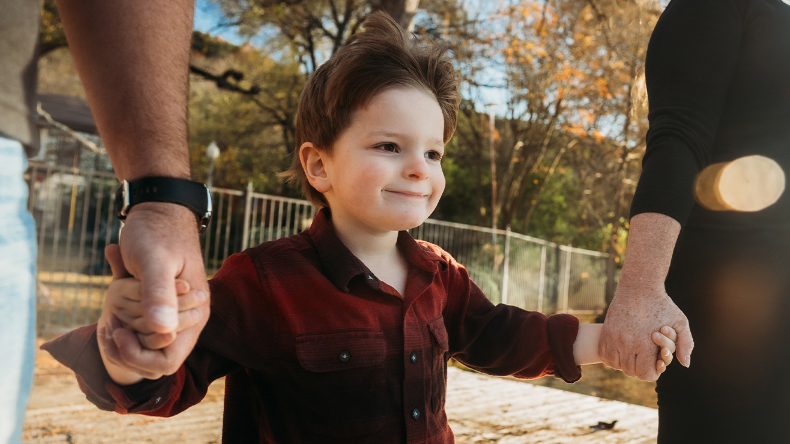 4-year-old boy (Levi Reeves) holding his parents hands during walk.