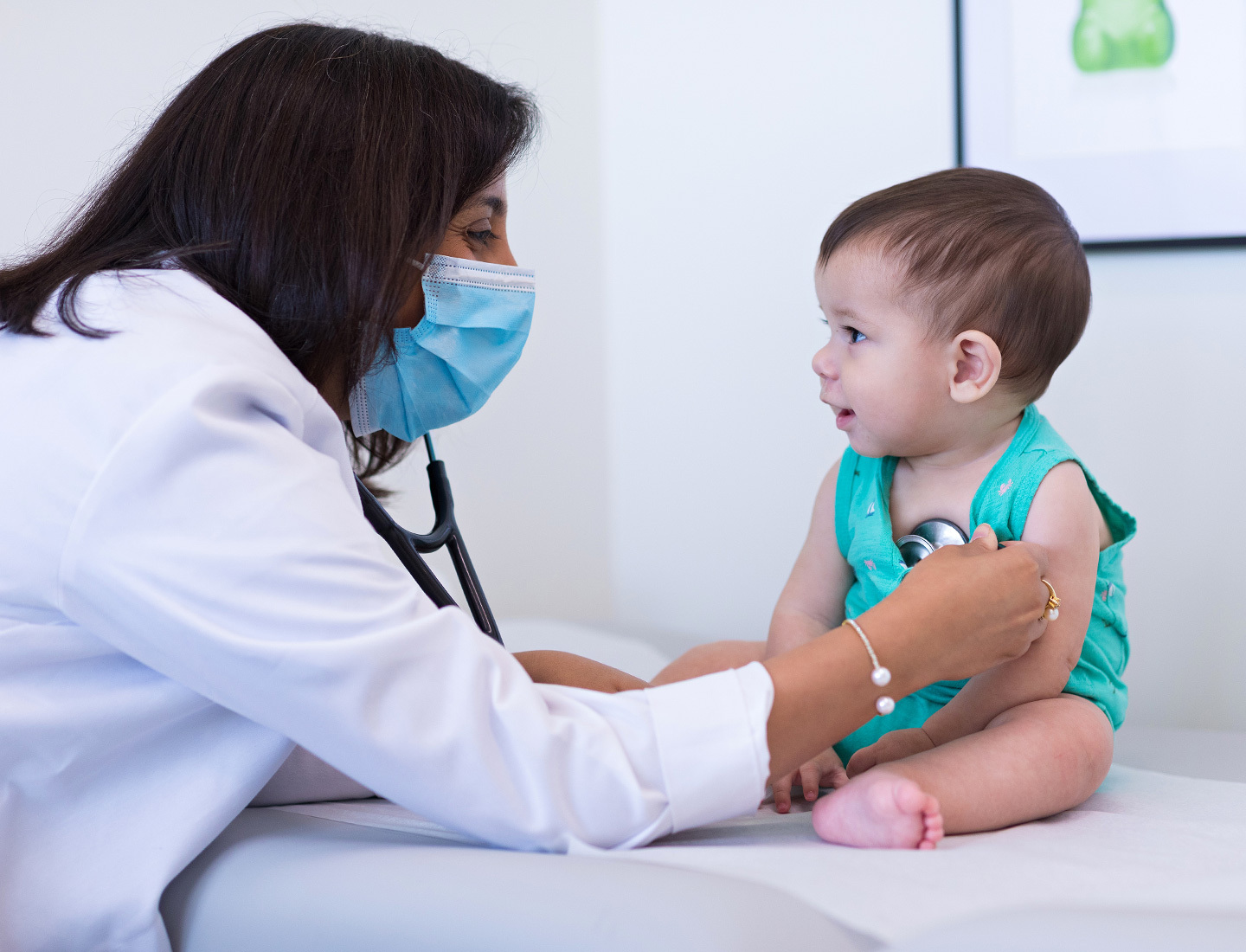 Pediatrician Alefiyah Malbari, MD, listening to an infant's heartbeat.