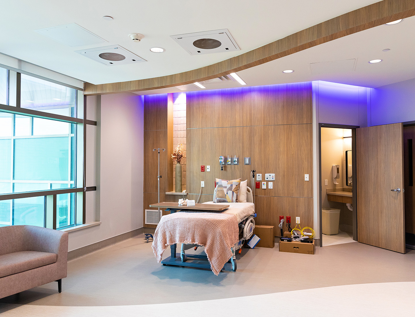 A patient room in the specialized delivery unit at Dell Children's has a bed, couch, large windows, and private bathroom.