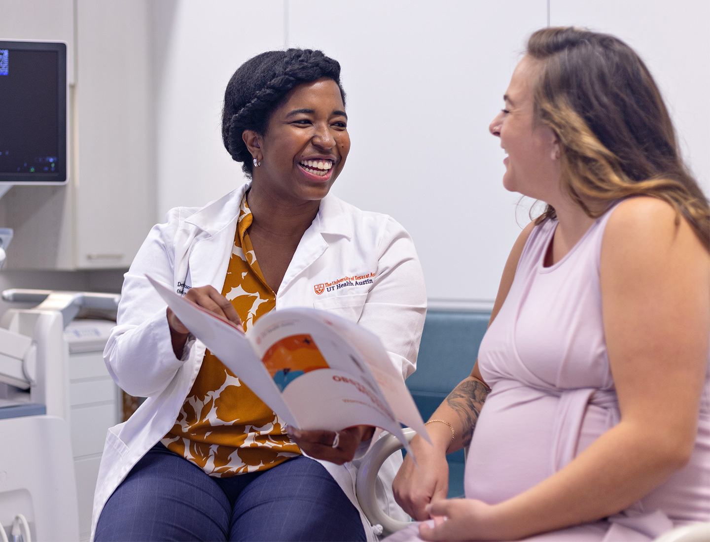 Obstetrician-gynecologist Denise Johnson, MD, smiling with a patient as they read a pamphlet together.