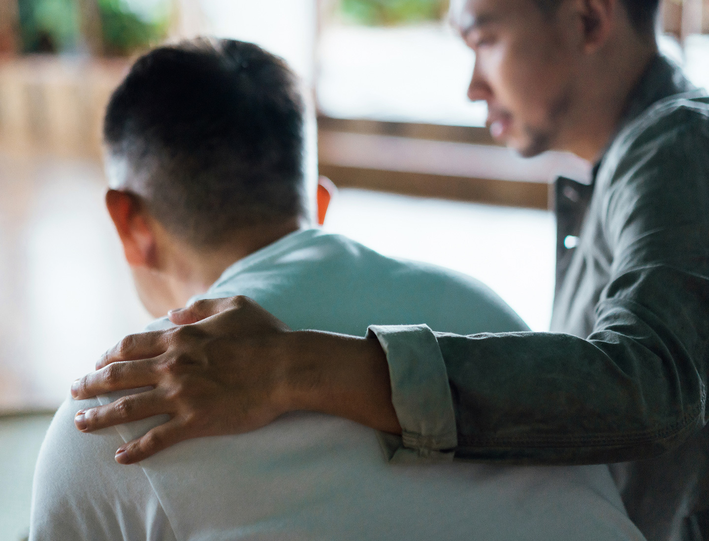 A young man places his arm around the shoulders of a loved one.