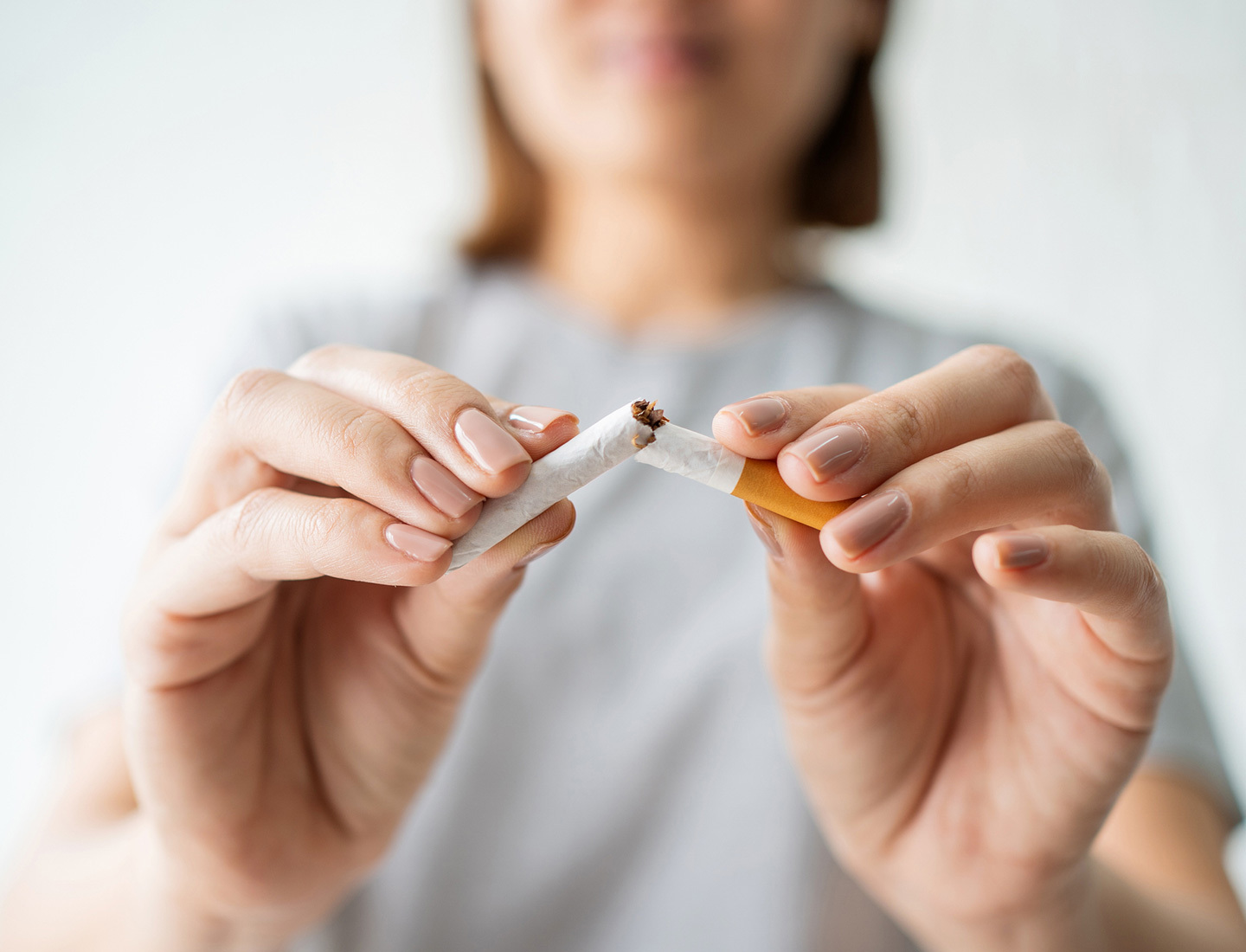 Close-up of a woman breaking a cigarette in half.