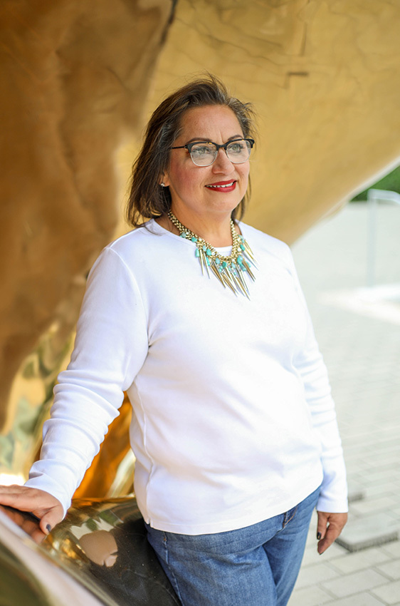 Kat, who works as a senior administrator for facilities at the Dell Medical School, stands facing the camera, smiling.