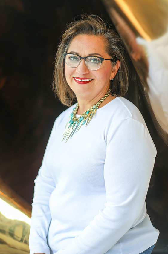 Kat, who works as a senior administrator for facilities at the Dell Medical School, stands facing the camera, smiling.