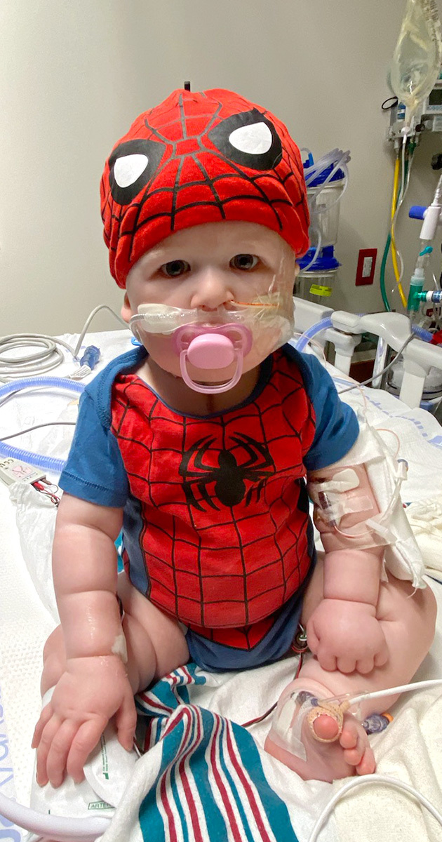 Baby Elias wearing a Spiderman cap and onesie in the hospital.