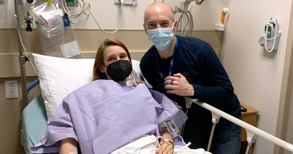 Victoria Threadgould's husband leans over her hospital bed and smiles alongside her in preop.