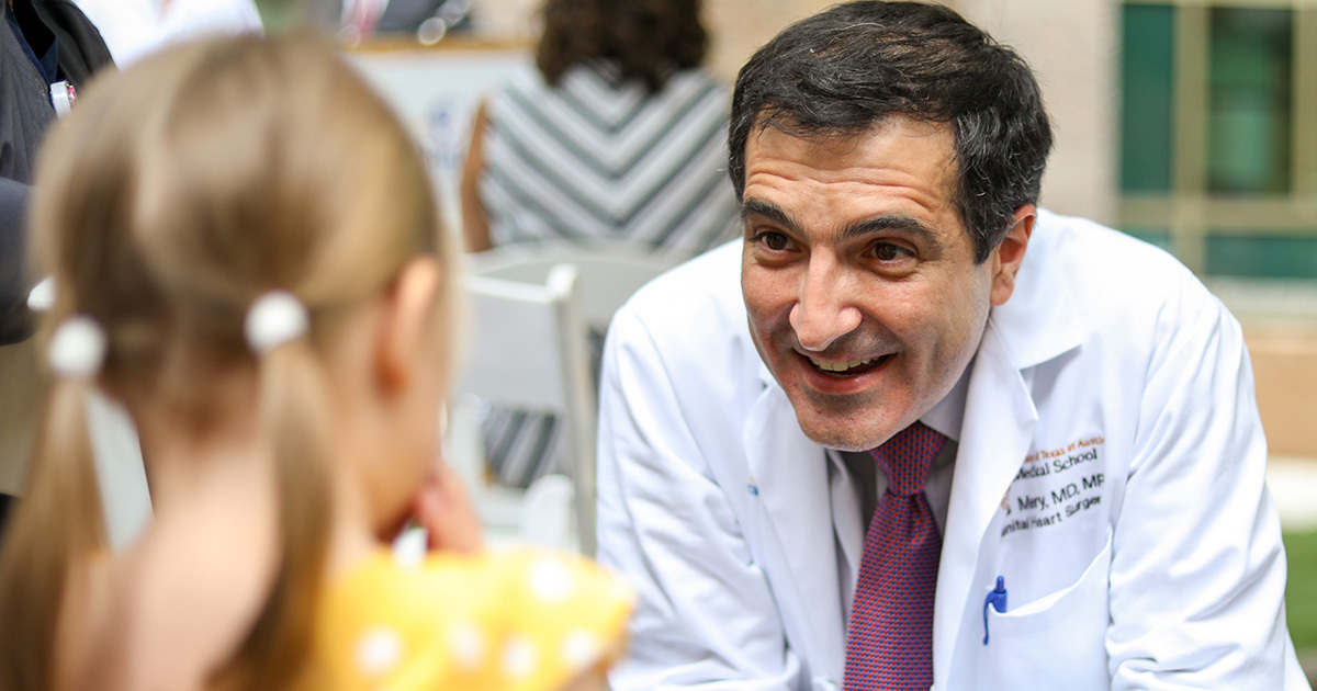 Carlos M. Mery, MD, smiling at a girl in pigtails.