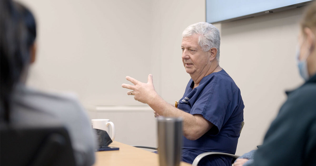 Dr. Kenneth J. Moise, Jr., addressing a group seated around a conference table.