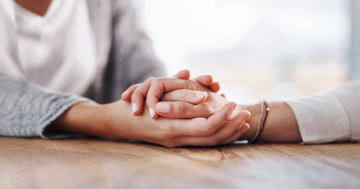 A close up of two women holding hands in a very supportive way.