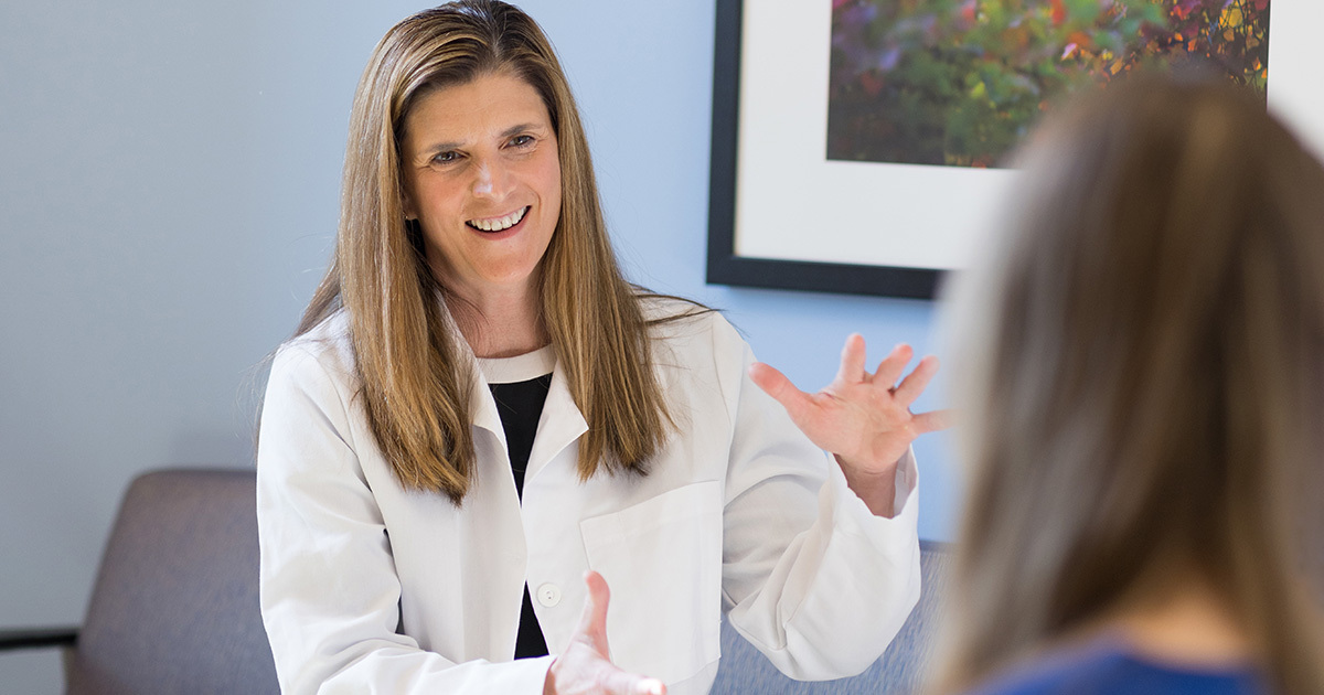 Dr. Nicole Turgeon wearing a white coat and speaking to a patient in the clinic.