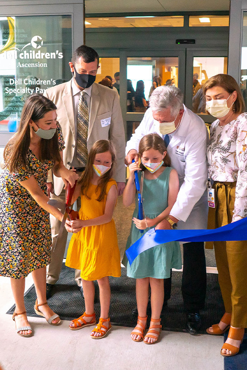 Amber Cessac and her twin daughters join Dr. Kenneth Moise for a ceremonial ribbon cutting