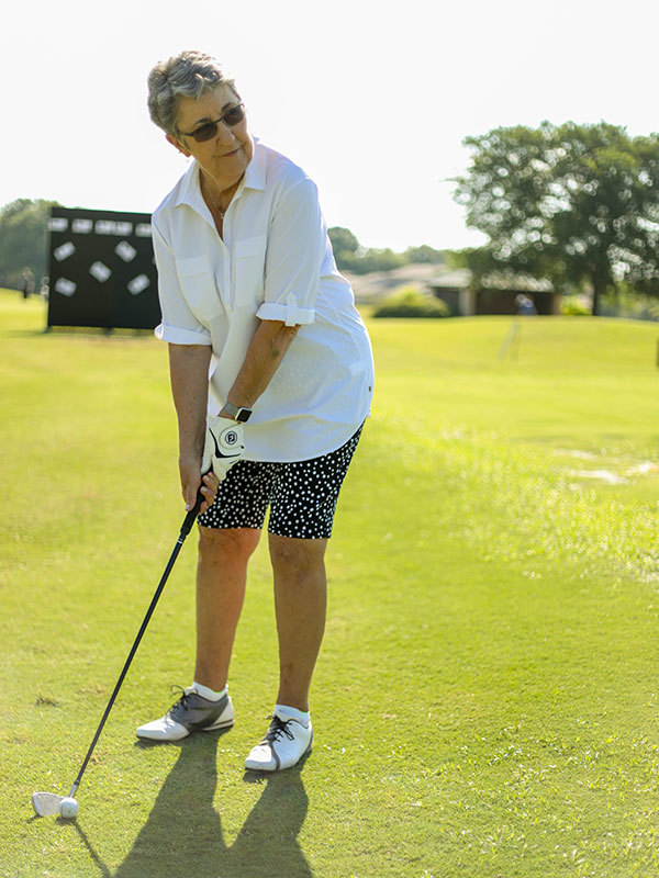 Chris, a knee patient at UT Health Austin, lines up a putt on a grassy golf course.