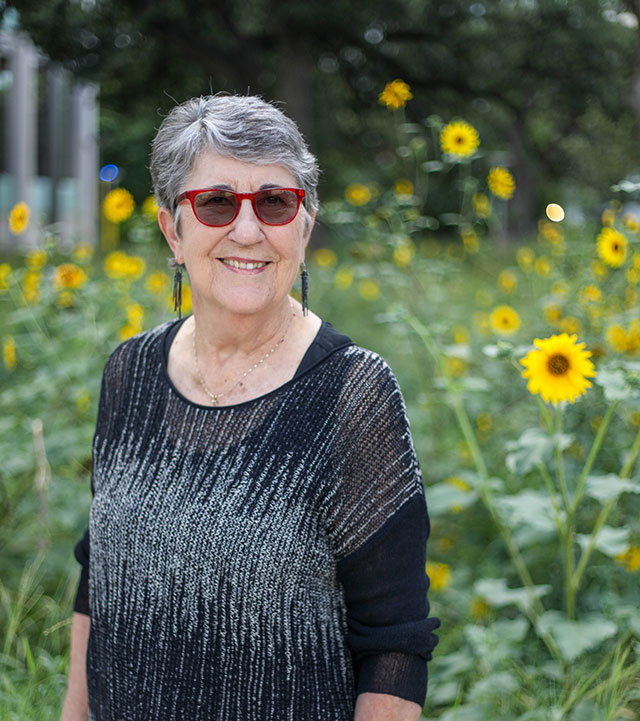 Chris, a knee patient at US Health Austin, stands smiling in a garden with sunflowers visible in the background.