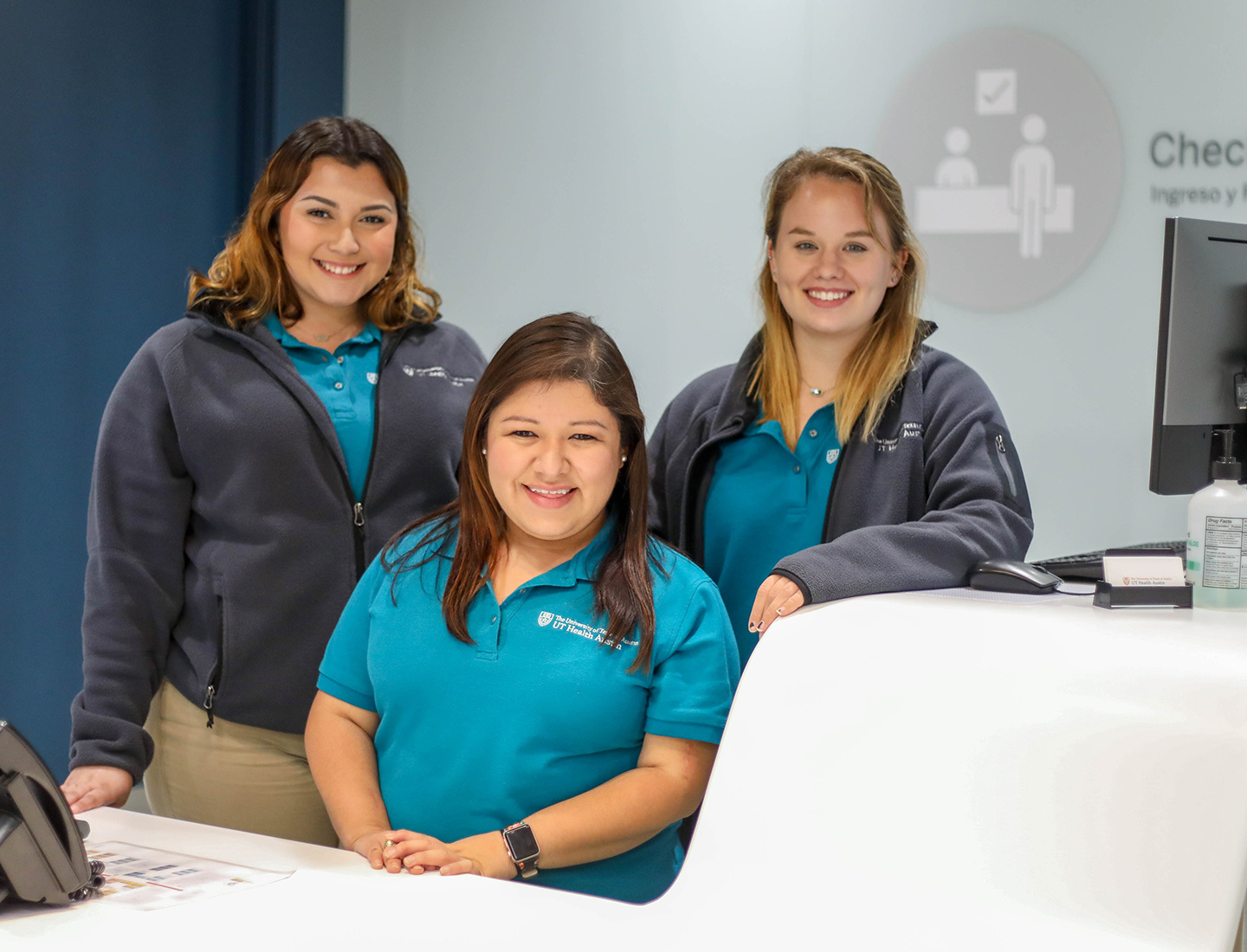 Three female members of UT Health Austin's concierge team smile at the camera.