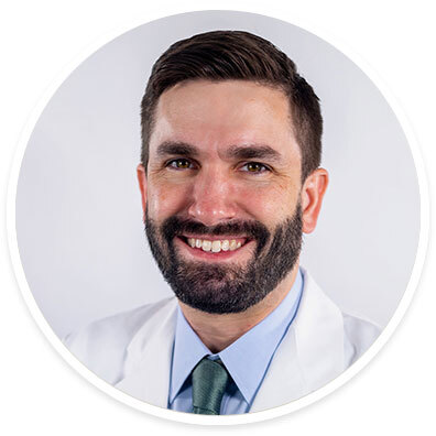 Pediatric neurologist Daniel Freedman, DO, wearing a white coat and smiling in front of a white backdrop.