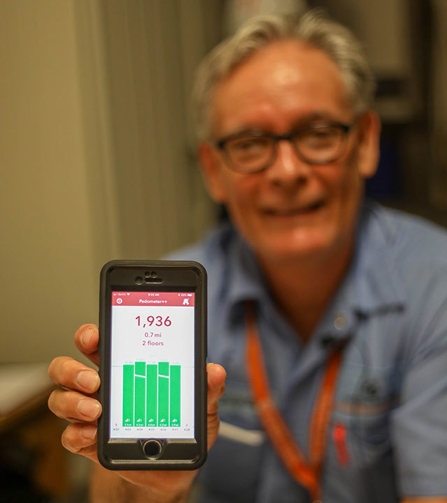 Eduardo, a patient at UT Health Austin's Musculoskeletal Institute, shows the screen of his smartphone, on which is displayed a pedometer app.