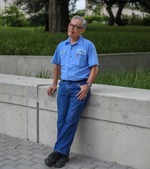 Eduardo, a patient at UT Health Austin's Musculoskeletal Institute, stands next to a retaining wall on the University of Texas at Austin campus.