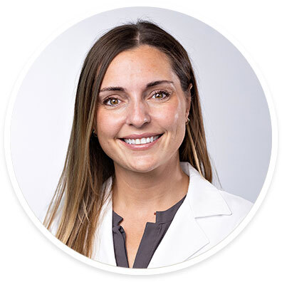 Surgeon Elisa Furay, MD, wearing a white coat and smiling in front of a white backdrop.