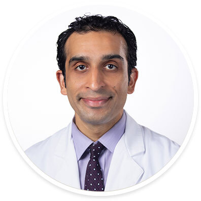 Urologic oncologist Harras Zaid, MD, wearing a white coat and smiling in front of a white backdrop.