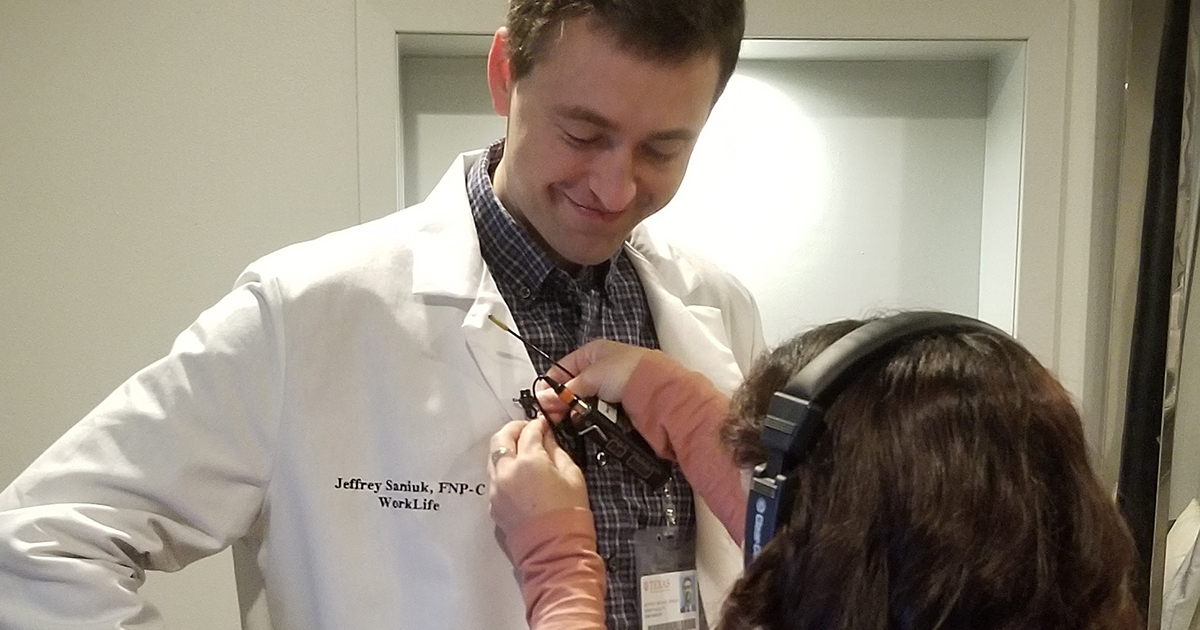 Jeff Saniuk, Nurse Practitioner with UT Health Austin's Walk-In Clinic, is seen having a lavalier microphone clipped to the collar of his lab coat.