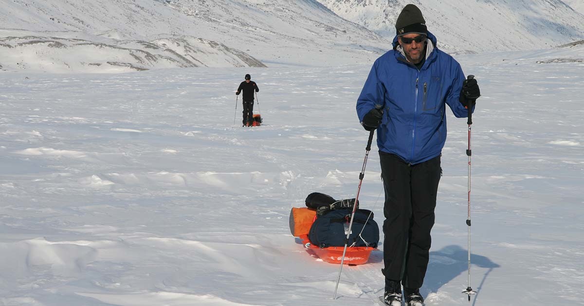 Jeff, a hip replacement patient with the Musculoskeletal Institute, is shown hiking across a glacier, pulling a sled.