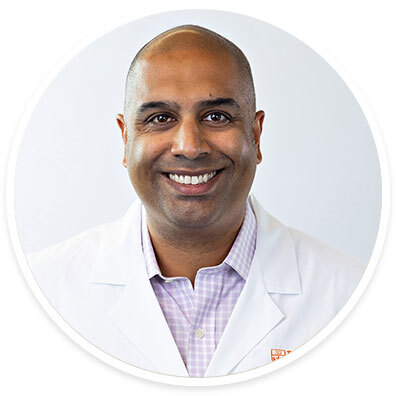 Colon and rectal surgeon S. Joga Ivatury, MD, MHA, wearing a white coat and smiling in front of a white backdrop.