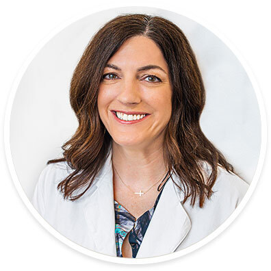 Surgical oncologist Kimberly Brown, MD, FACS, wearing a white coat and smiling in front of a white backdrop.