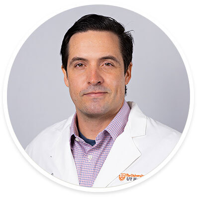 Pediatric psychiatrist Ryan Brown, MD, wearing a white coat and posing in front of a white backdrop.