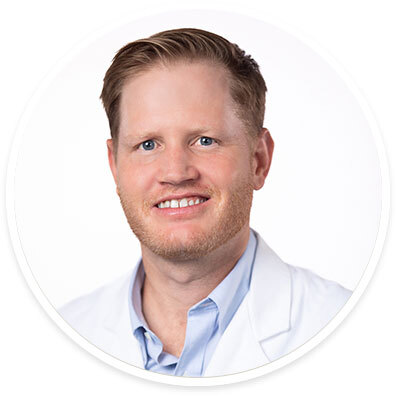 Surgeon Samuel E. "Rhett" Long, III, MD, FACS, wearing a white coat and smiling in front of a white backdrop.