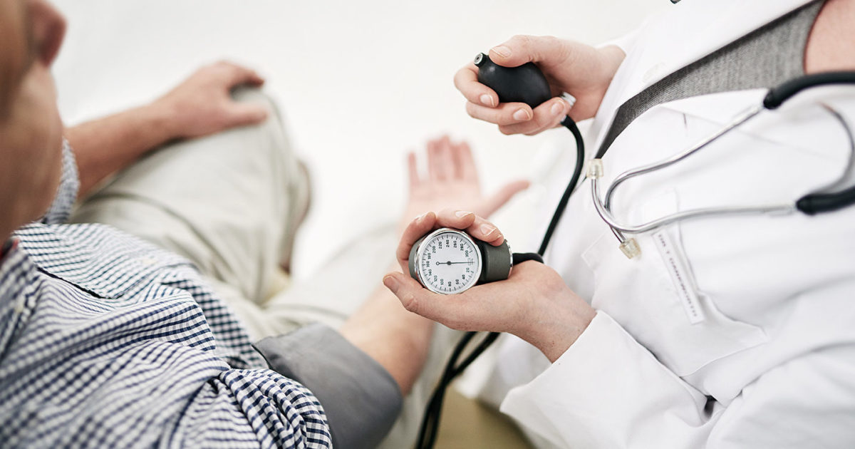 A man has his blood pressure checked by a clinician.