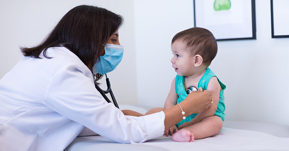 Pediatrician Alefiyah Malbari, MD, listening to an infant's heartbeat.