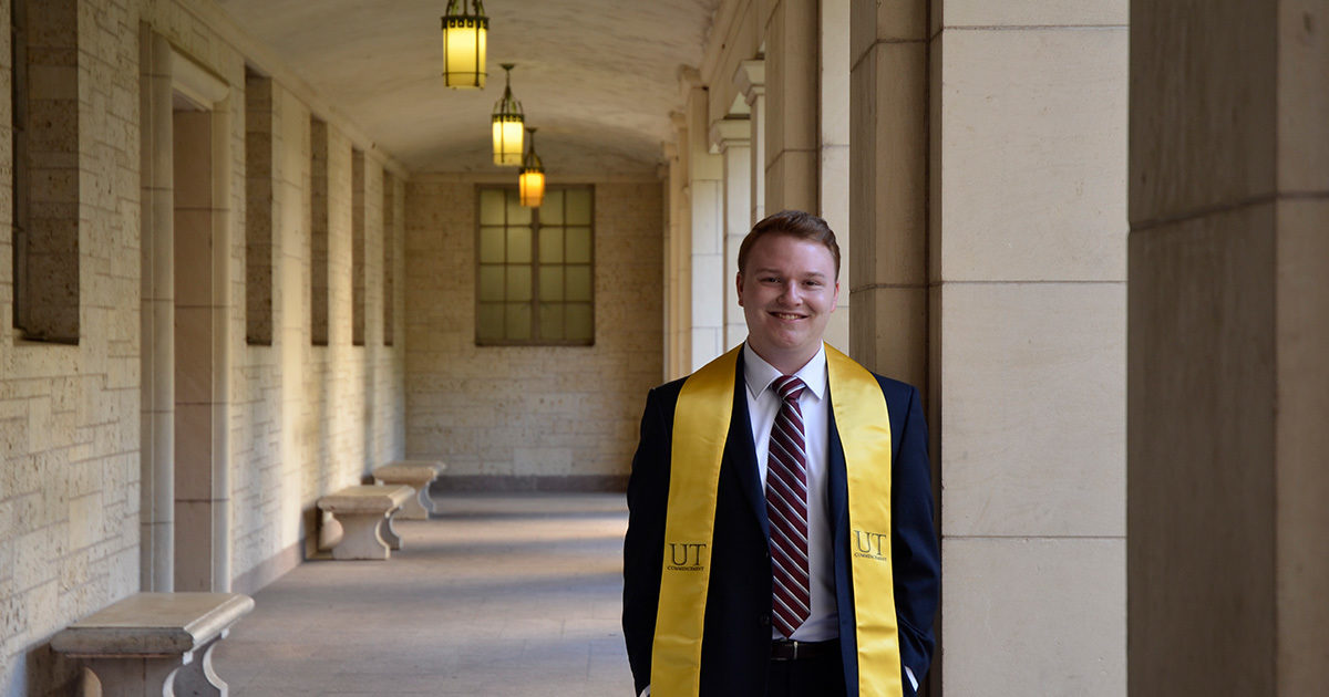 Mason, a patient in Digestive Health, stands in an outdoor corridor with his University of Texas yellow stole while smiling.