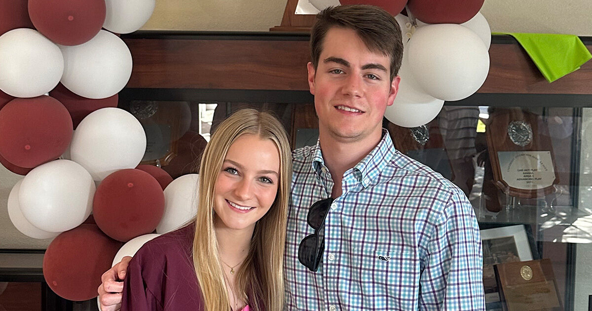 Cole Perry posing with a friend in front of a balloon arch.