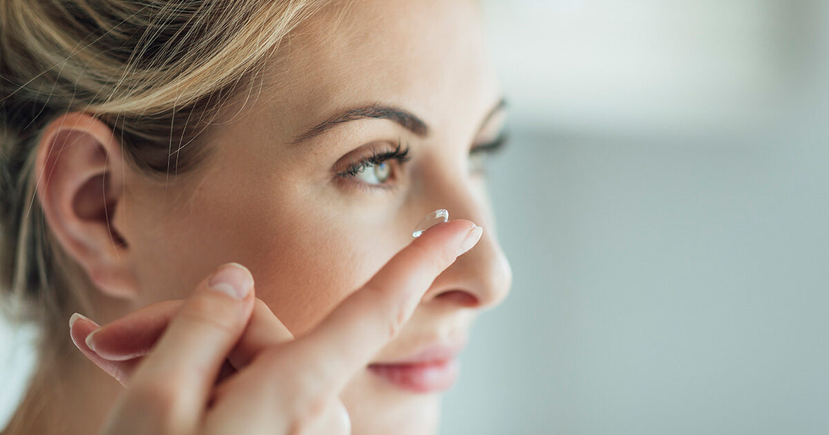 Close up of a woman bringing a contact lens up to her eye.