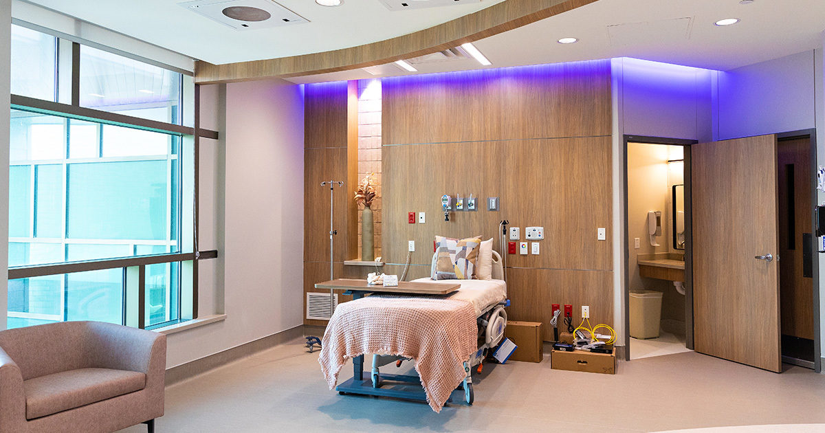 A patient room in the specialized delivery unit at Dell Children's has a bed, couch, large windows, and private bathroom.