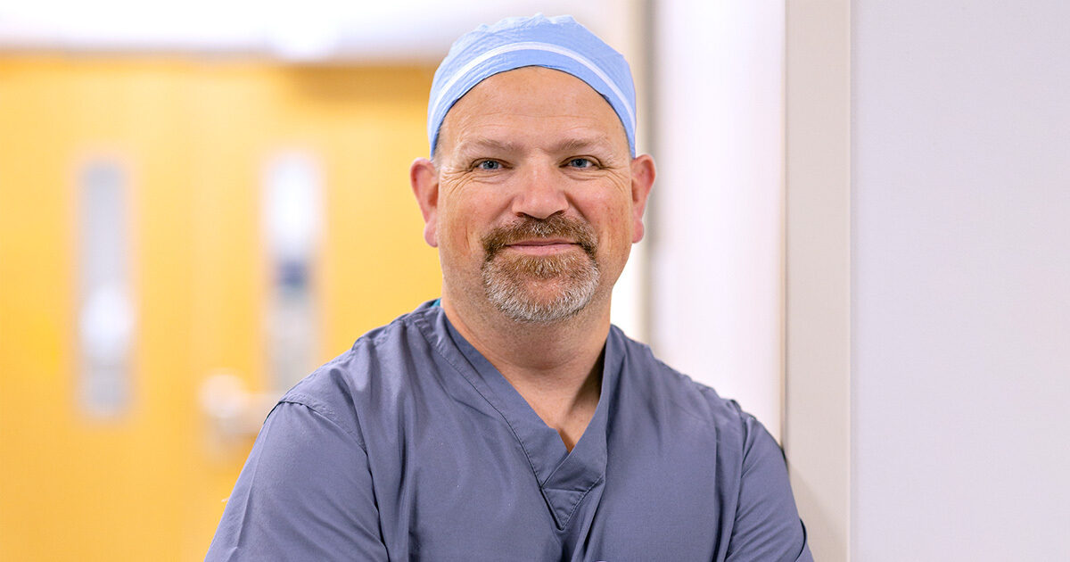 Karl Koenig, MD, wearing scrubs and a surgical cap.