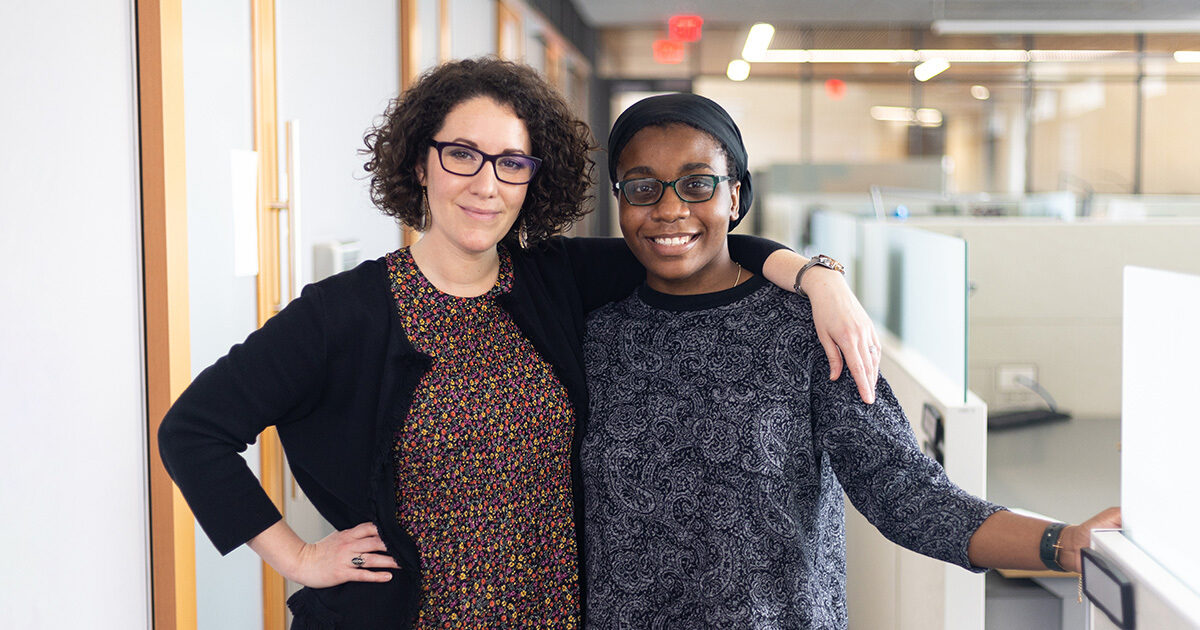 Dr. Leorah Freeman and Helen Onuorah are smiling and standing arm in arm in their lab.