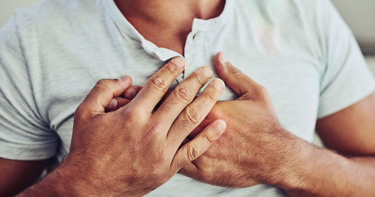 A man with heartburn holds his crossed hands over his chest.