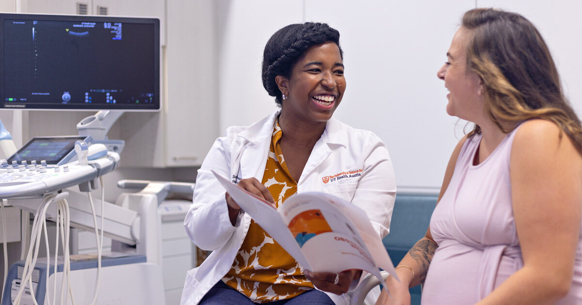 Obstetrician-gynecologist Denise Johnson, MD, smiling with a patient as they read a pamphlet together.