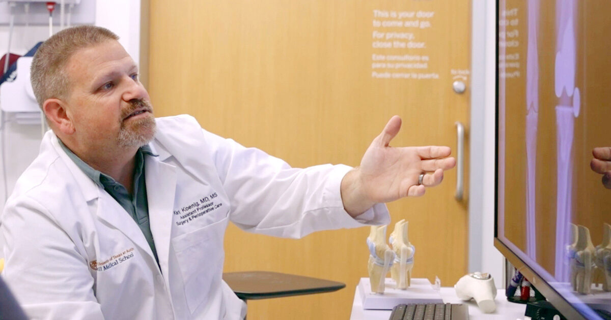 Orthopedic surgeon Karl Koenig, MD, gesturing towards x-ray images on a monitor.