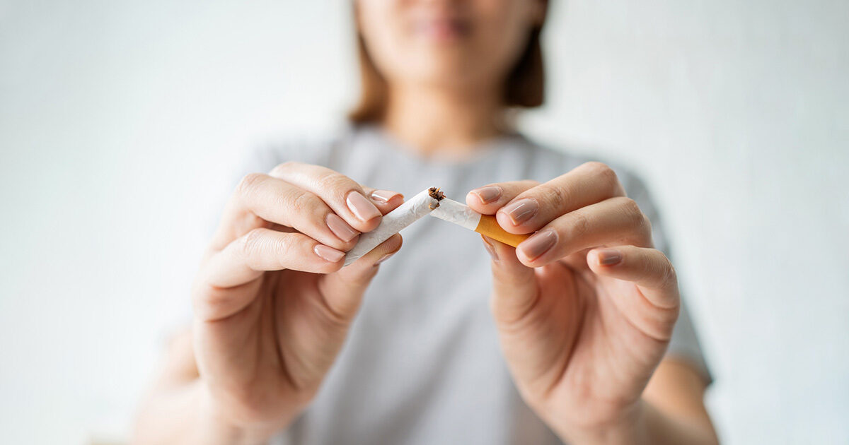 Close-up of a woman breaking a cigarette in half.