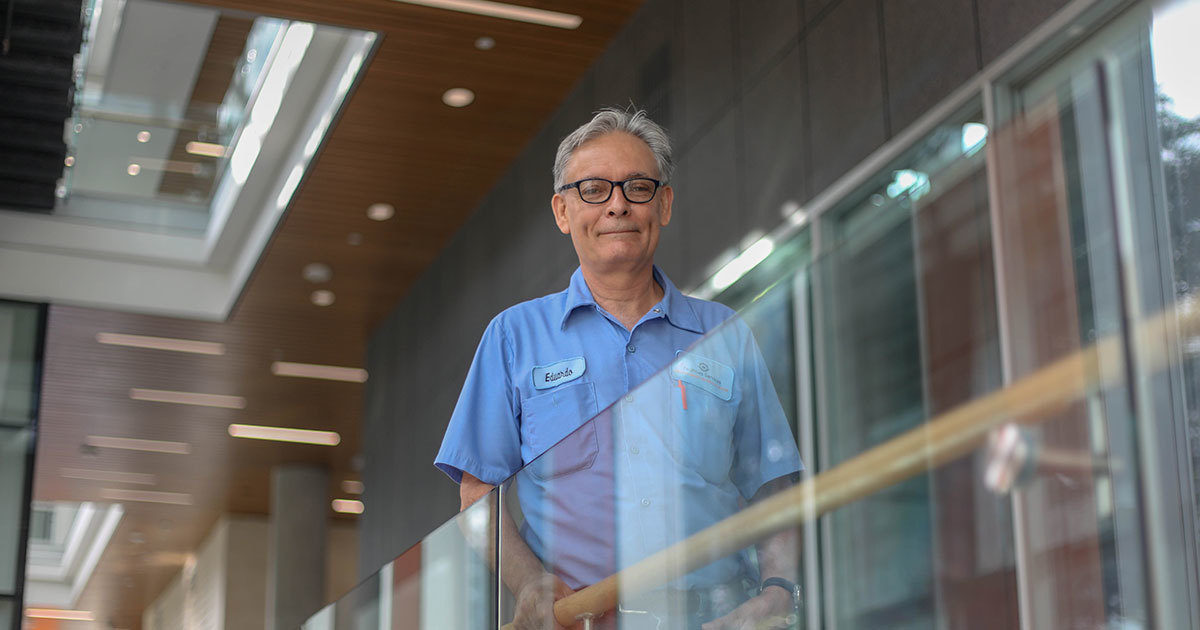 Eduardo, a patient at UT Health Austin's Musculoskeletal Institute, stands next to a railing in the building where he works.