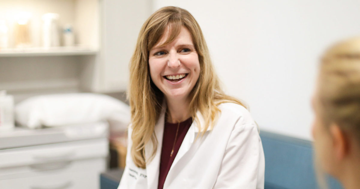 A female clinician smiles at a patient.
