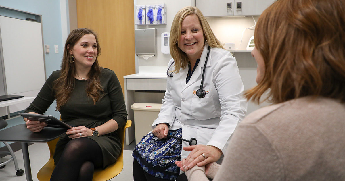 Clinicians at UT Health Austin's Comprehensive Memory Center smiles while consulting with a patient.