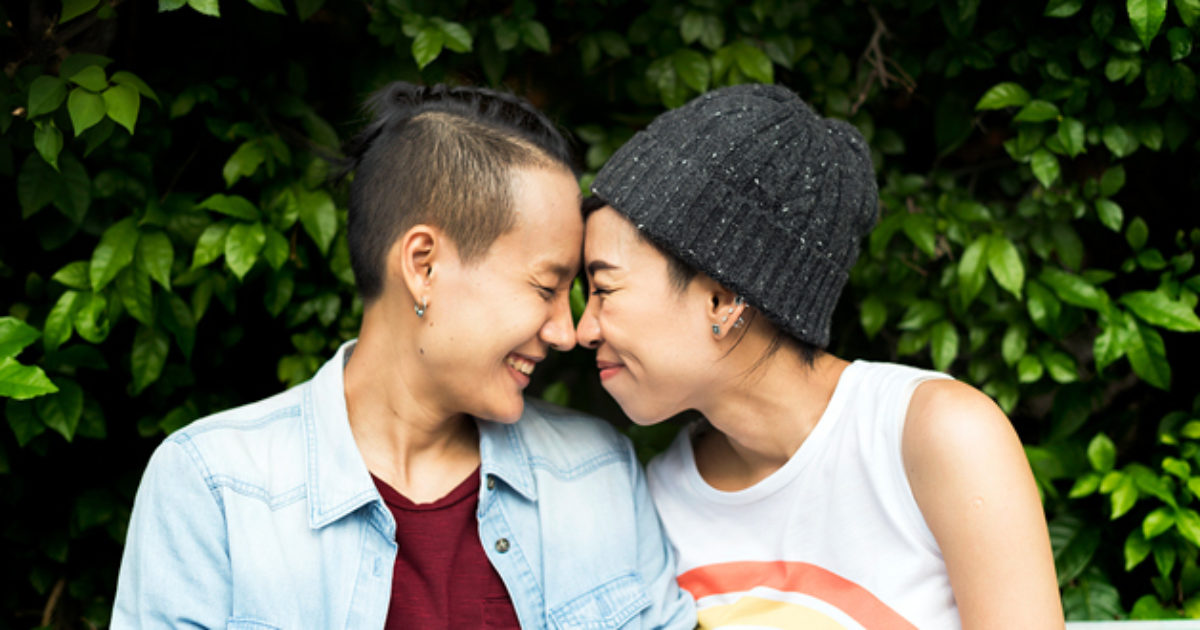 Two young women embrace and touch noses in an expression of affection and love.