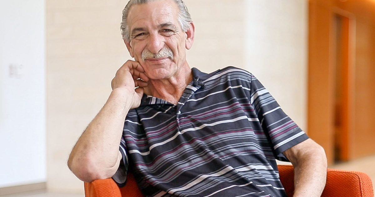 Michael, a patient at the Musculoskeletal Institute, sits in a chair and smiles into the camera.